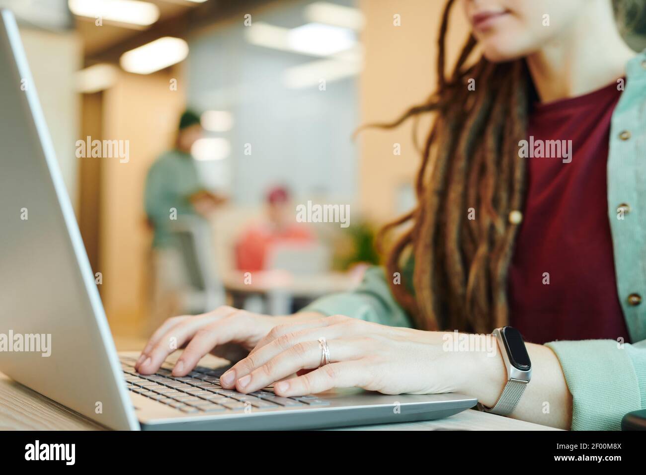 Les mains de jeunes femmes contemporaines de bureau directeur en vêtements décontractés plus clavier d'ordinateur portable lors de la présentation par son lieu de travail Banque D'Images