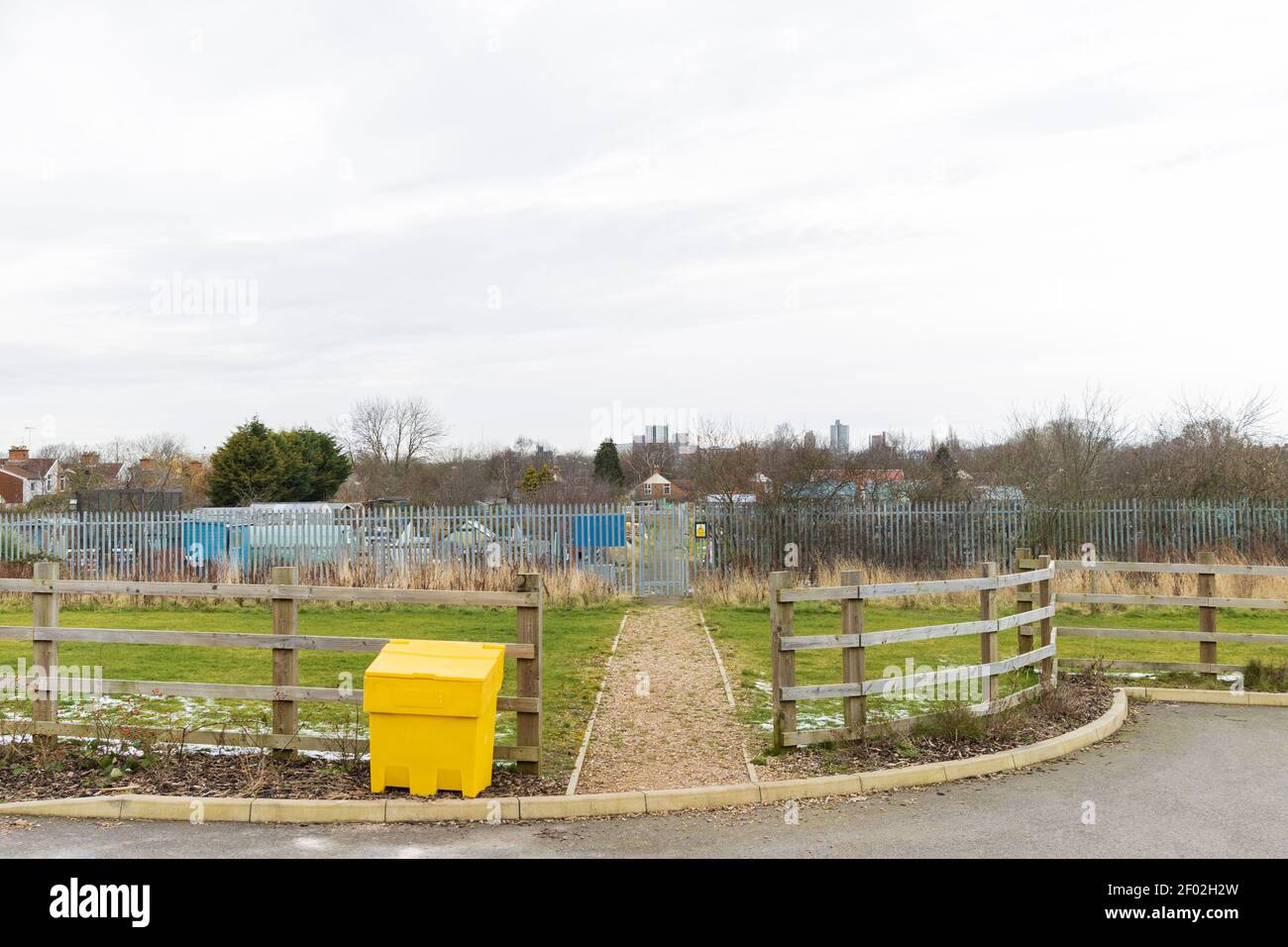 Zone de pelouse, porte d'accès aux allotements, clôture en acier, hangars, et de grands bâtiments à l'Université de Leicester, montrant le centre-ville de Leicester horizon. Banque D'Images