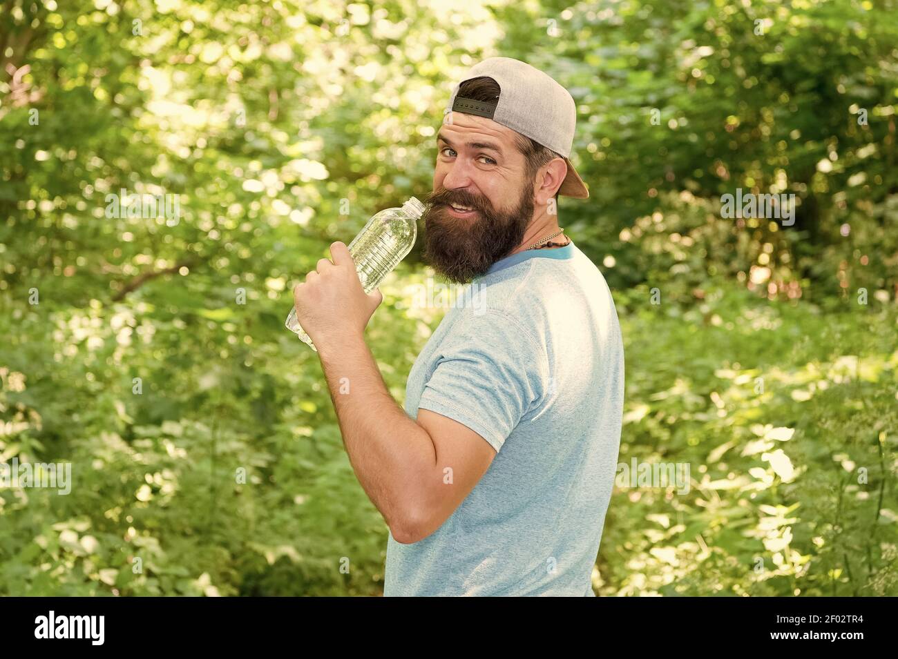 Hydrate ou mourir. Hipster brutal en forêt. Découvrez de nouveaux endroits. Temps pour pique-niquer. Guy boit de l'eau. Homme barbu en cap. Vacances d'été en camping. Homme randonnée. Homme envie d'avoir soif. Banque D'Images