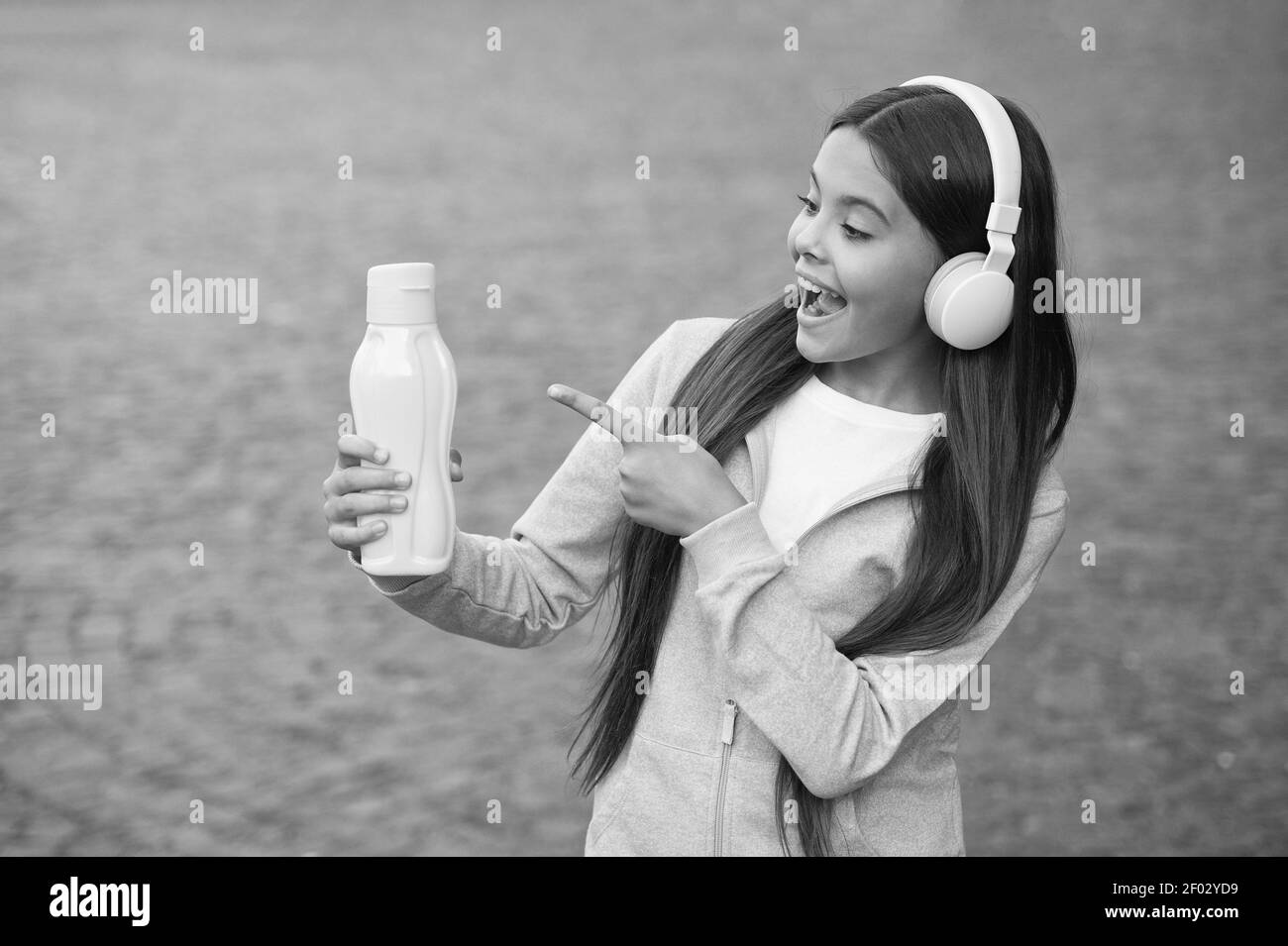 bonne adolescente pointant le doigt sur la bouteille d'eau allant boire, se rafraîchir. Banque D'Images