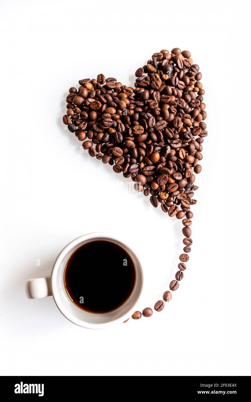 Pour une pause-café. Un coeur fait de grains de café volant comme un petit ballon d'une tasse sur un fond blanc. Banque D'Images
