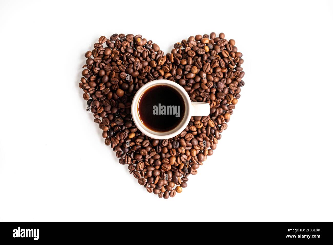 Une pause pour les amateurs de café. Une tasse de café à l'intérieur d'un coeur fait de grains de café. Composition de la couche plate sur fond blanc. Banque D'Images