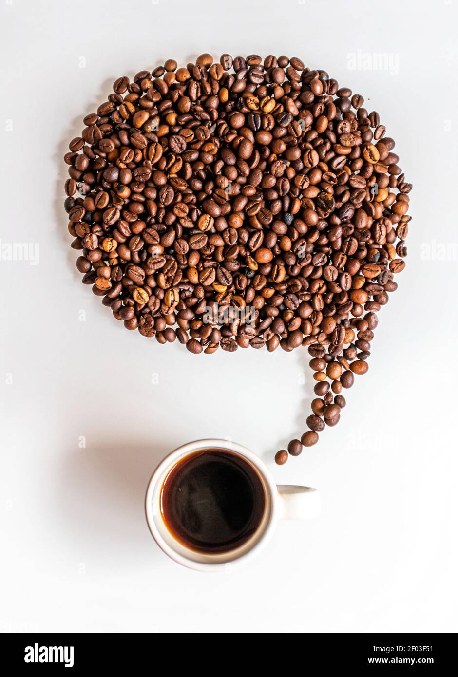 Un ballon de réflexion fait de grains de café sur une tasse sur un fond blanc. Pour exprimer vos idées de café. Banque D'Images