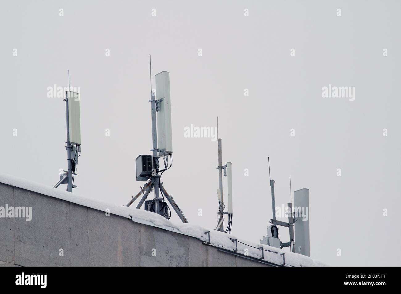 Antenne de réseau mobile de la station de base sur un toit d'un immeuble résidentiel contre un ciel gris. 3g, 4g, 5 g. Photo avec espace vide pour le texte et le design. Banque D'Images
