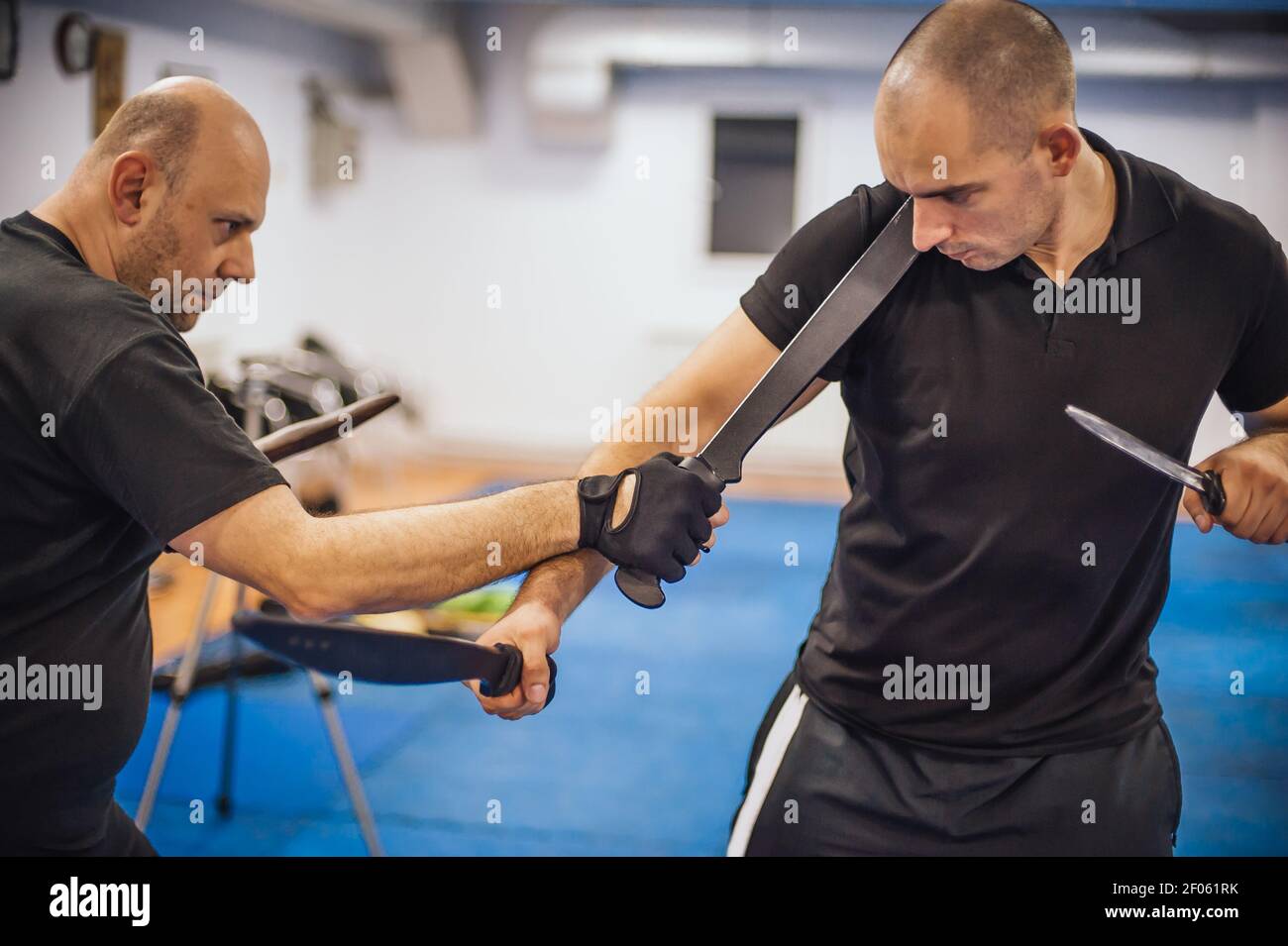 Instructeur et étudiant pratique une longue épée et couteau philippin escrima technique de combat. Démonstration d'arts martiaux Banque D'Images