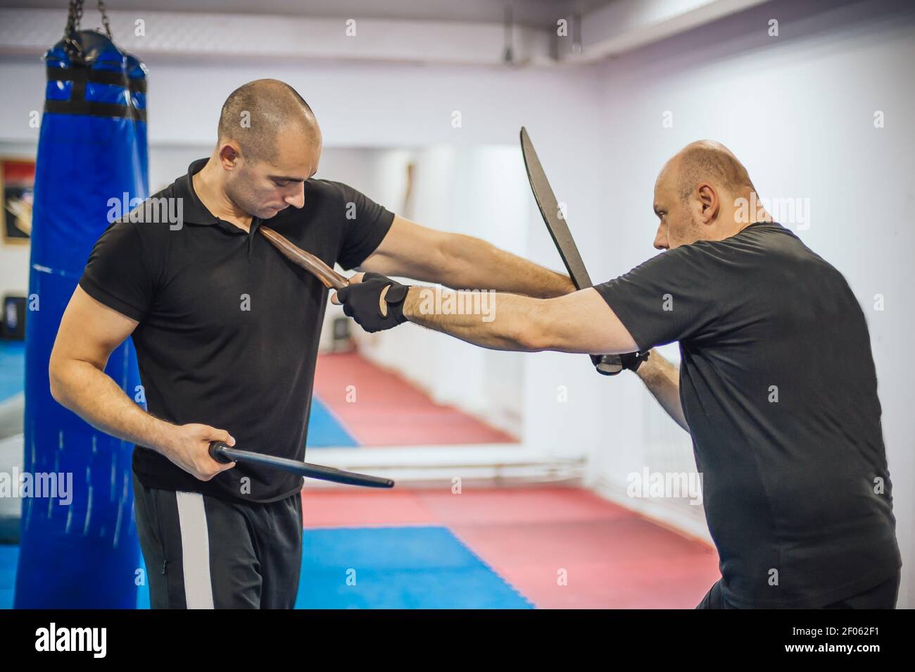 Instructeur et étudiant pratique une longue épée et couteau philippin escrima technique de combat. Démonstration d'arts martiaux Banque D'Images