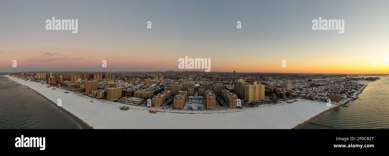 Vue aérienne d'une plage enneigée de Coney Island Beach pendant l'hiver au lever du soleil à Brooklyn, New York. Banque D'Images