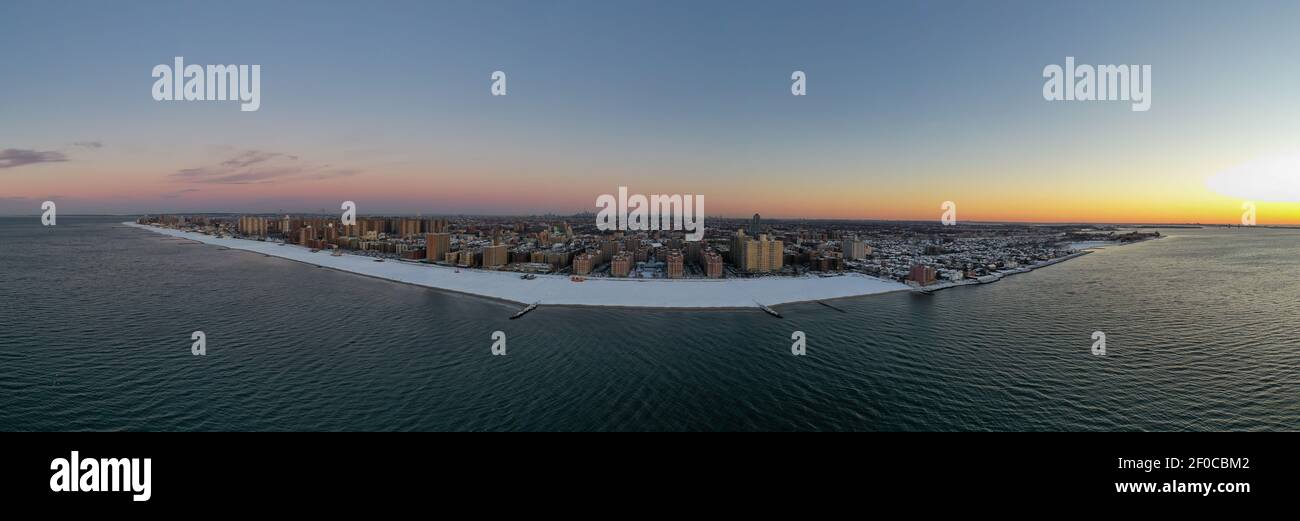 Vue aérienne d'une plage enneigée de Coney Island Beach pendant l'hiver au lever du soleil à Brooklyn, New York. Banque D'Images