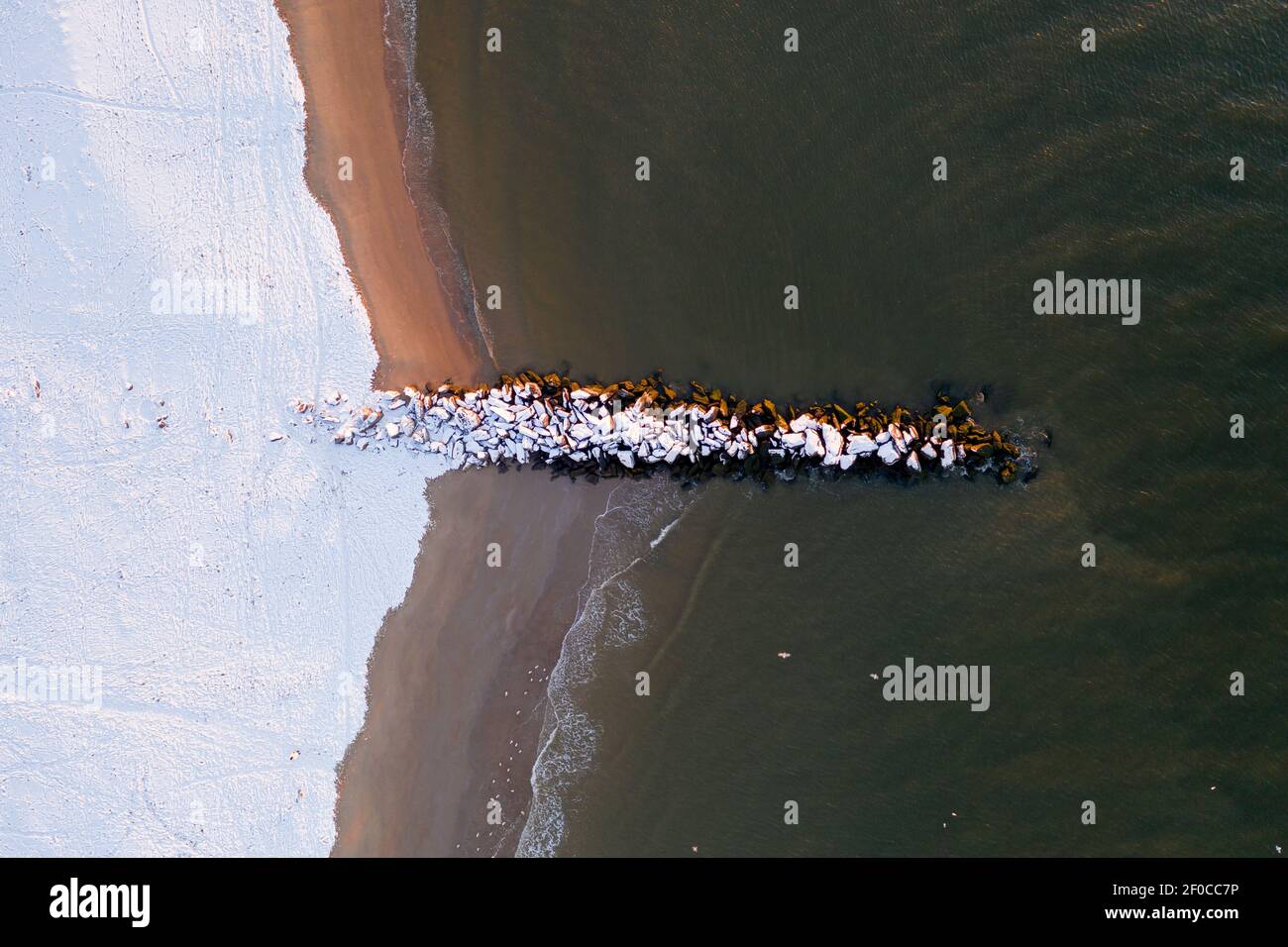 Vue aérienne d'une plage enneigée de Coney Island Beach pendant l'hiver au lever du soleil à Brooklyn, New York. Banque D'Images