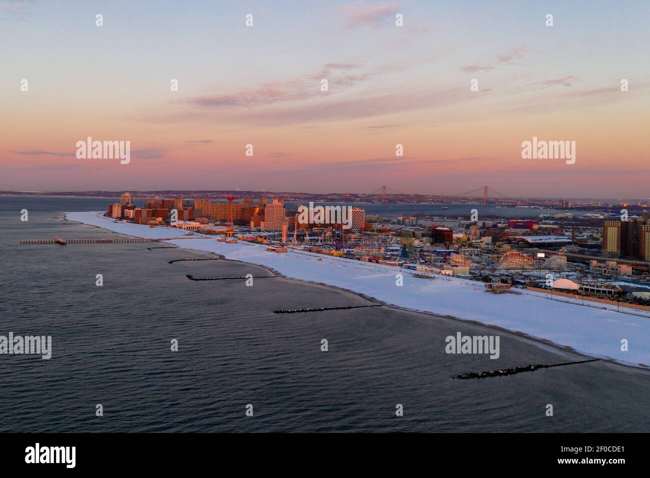 Vue aérienne d'une plage enneigée de Coney Island Beach pendant l'hiver au lever du soleil à Brooklyn, New York. Banque D'Images