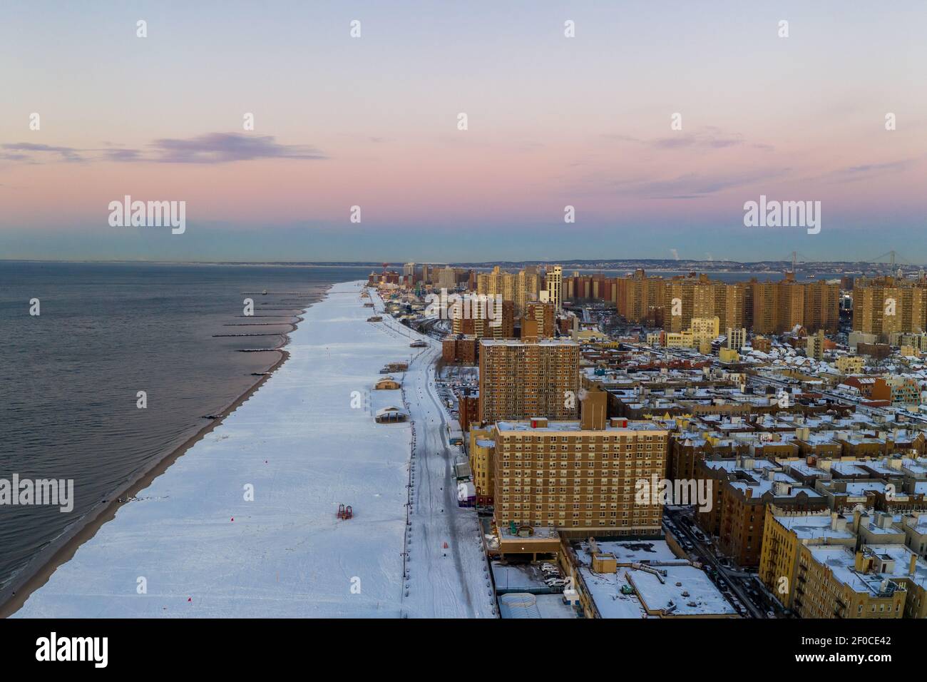 Vue aérienne d'une plage enneigée de Coney Island Beach pendant l'hiver au lever du soleil à Brooklyn, New York. Banque D'Images