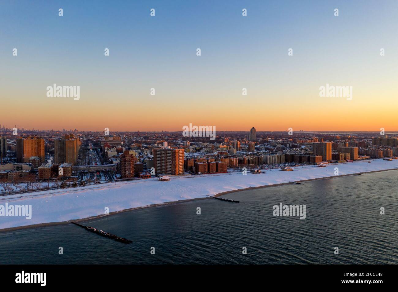 Vue aérienne d'une plage enneigée de Coney Island Beach pendant l'hiver au lever du soleil à Brooklyn, New York. Banque D'Images