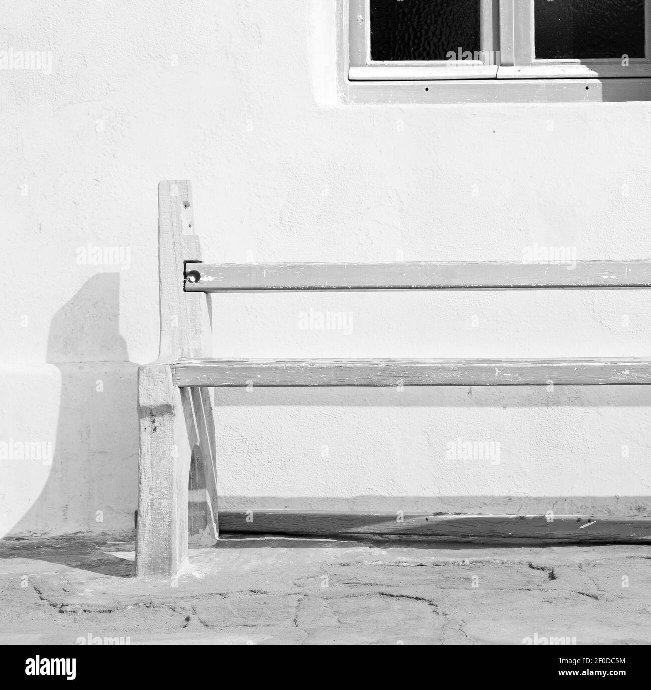 Chaise dans l'île de grèce de paros vieux banc près un mur antique en brique et un pavé en pierre Banque D'Images