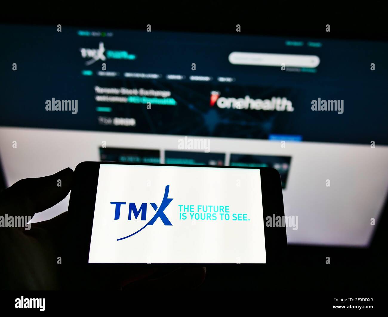 Personne détenant un smartphone avec le logo de la société canadienne de services financiers TMX Group Limited à l'écran devant le site Web. Mise au point sur l'affichage du téléphone. Banque D'Images
