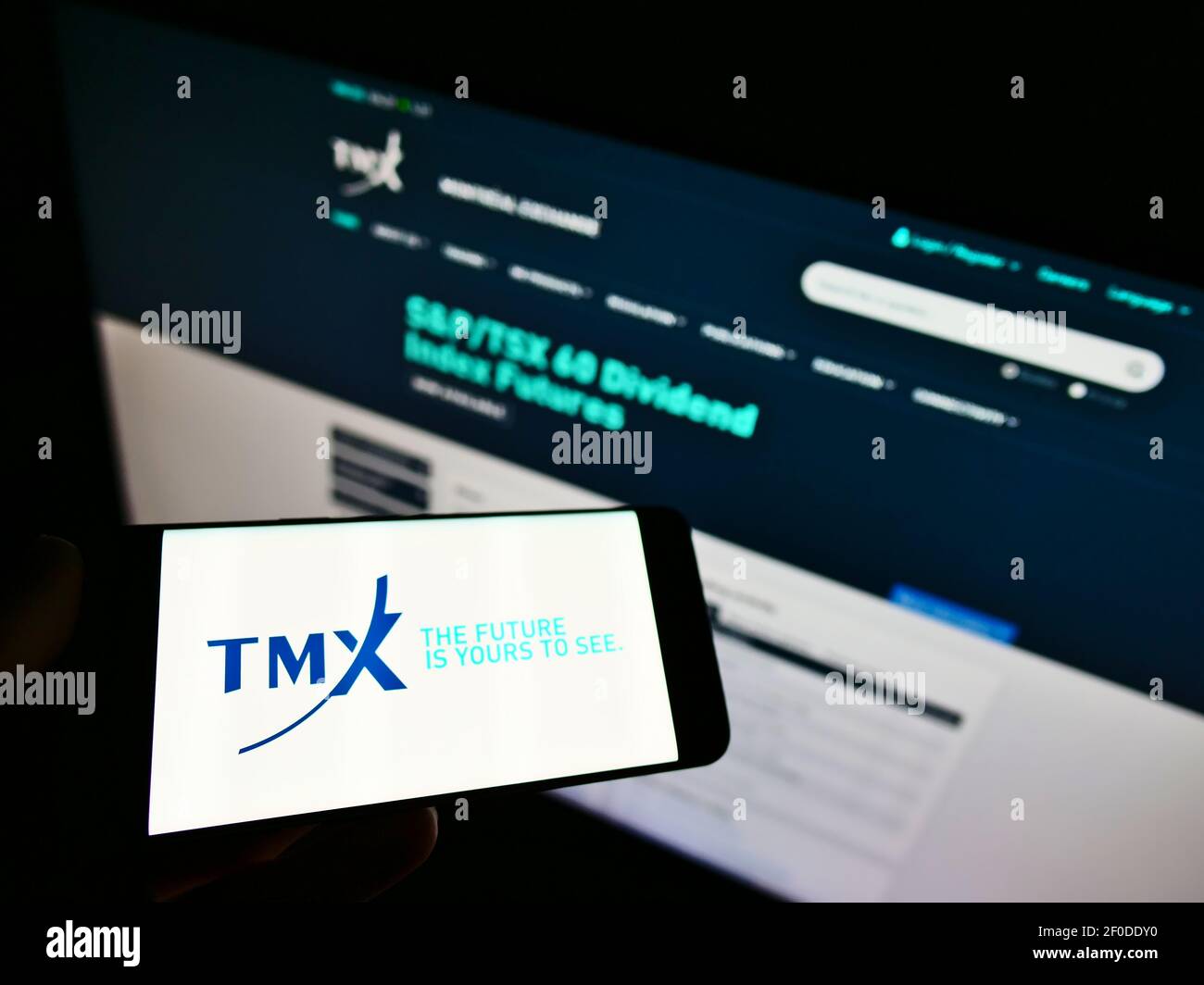 Personne tenant un téléphone cellulaire avec le logo de la société canadienne de services financiers TMX Group Ltd à l'écran devant la page Web. Mise au point sur l'affichage du téléphone. Banque D'Images