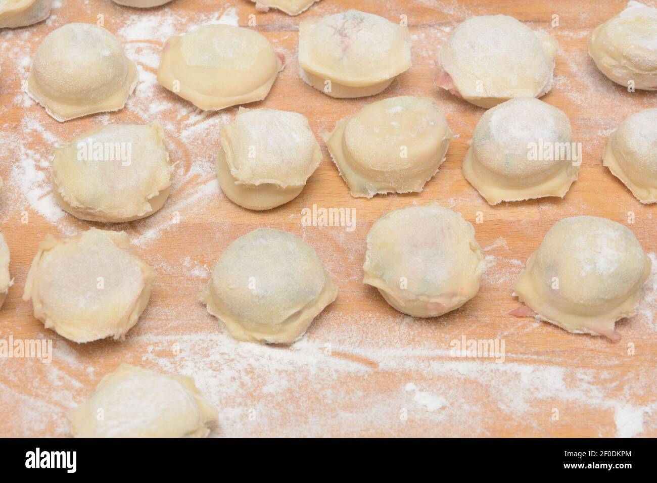 Boulettes faites maison avec de la viande sur une table en bois et de la farine. Raviolis pour cuisiner le dîner. Gros plan, mise au point sélective. Banque D'Images