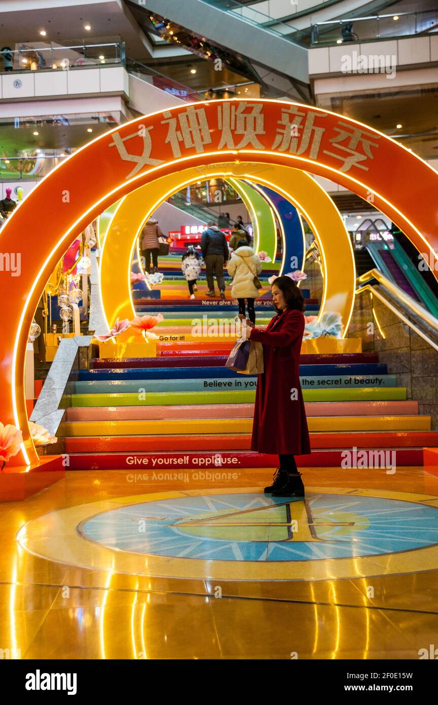 Une femme d’âge moyen prend un selfie devant un tunnel coloré pour la Journée des femmes dans le Super Brand Mall de Shanghai à Lujiazui, dans le district de Pudong, en Chine Banque D'Images