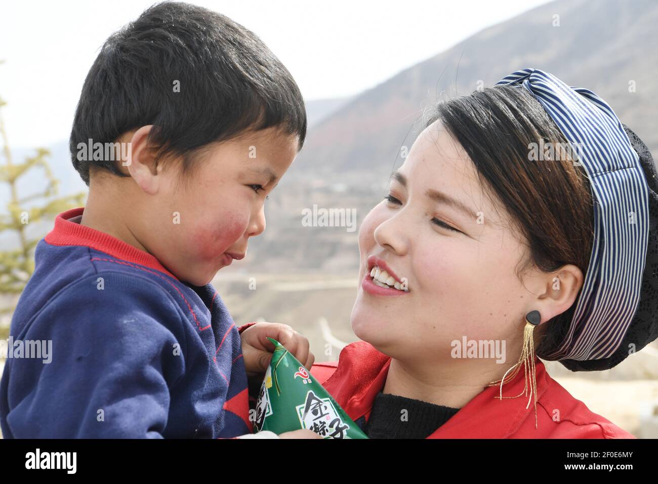 (210307) -- DONGXIANG, 7 mars 2021 (Xinhua) -- Ma Linhong tient son enfant pendant le temps de repos à midi dans le village Nanyangwa du comté de Dongxiang de la préfecture autonome Linxia hui, province de Gansu, dans le nord-ouest de la Chine, le 4 mars 2021. Ma Linhong, 26 ans, gagne environ 6,000 yuans (environ 923 dollars américains) par mois dans un atelier du village de Nanyangwa. Depuis que Ma Linhong a gagné la première place dans le système de piecwork pendant plusieurs mois de suite, elle a été promue d'une travailleuse ordinaire à la tête de l'atelier. Dans le passé, Ma faisait du travail agricole et des tâches à domicile, sans moyen de gagner de l'argent supplémentaire. Arrière Banque D'Images