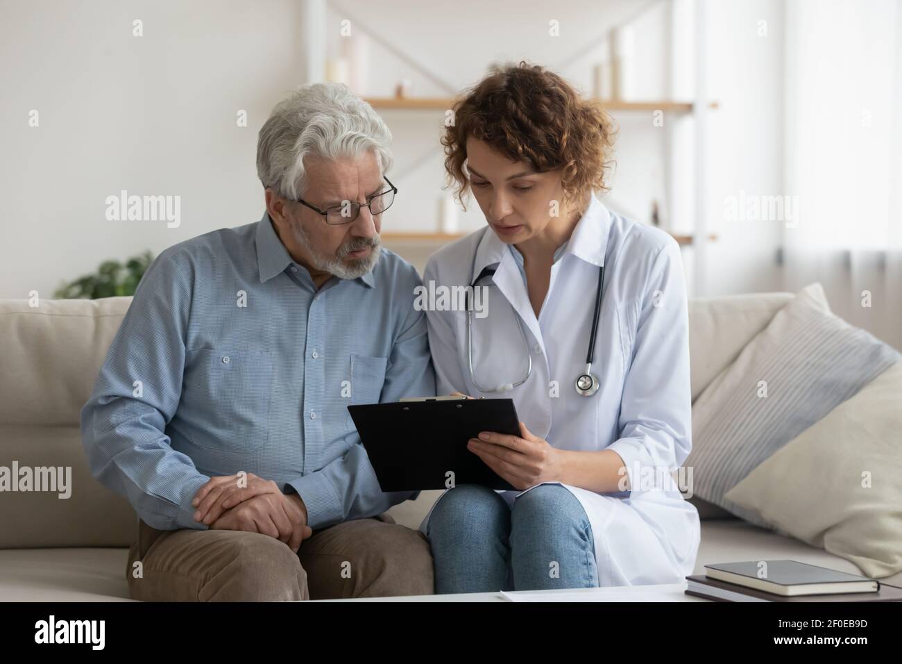 Une infirmière féminine consulte un patient d'homme mûr à la maison Banque D'Images