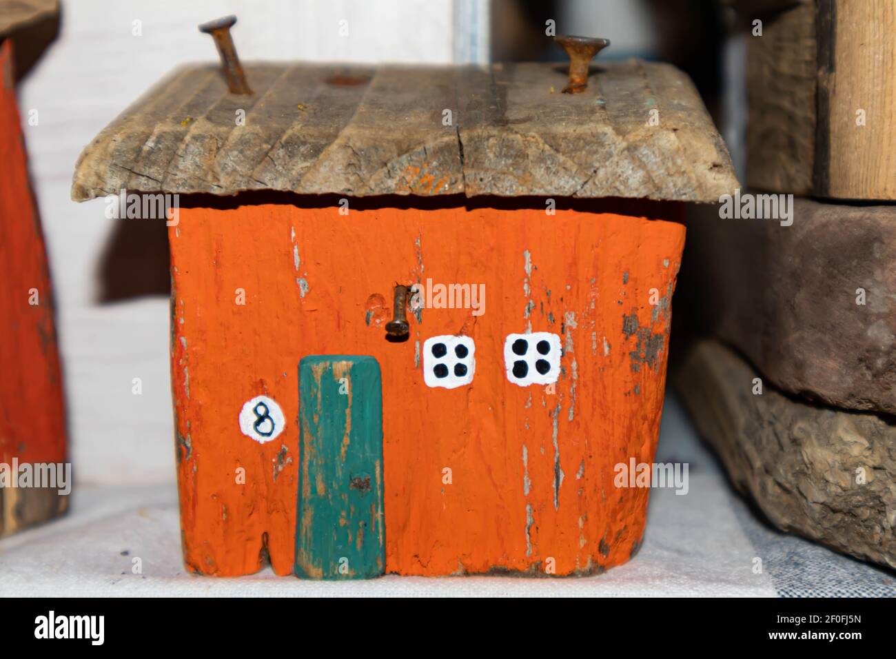 Ancienne maison en bois orange. Les clous rouillés sont entraînés dans le toit. Petites fenêtres blanches. Cabane miniature Banque D'Images