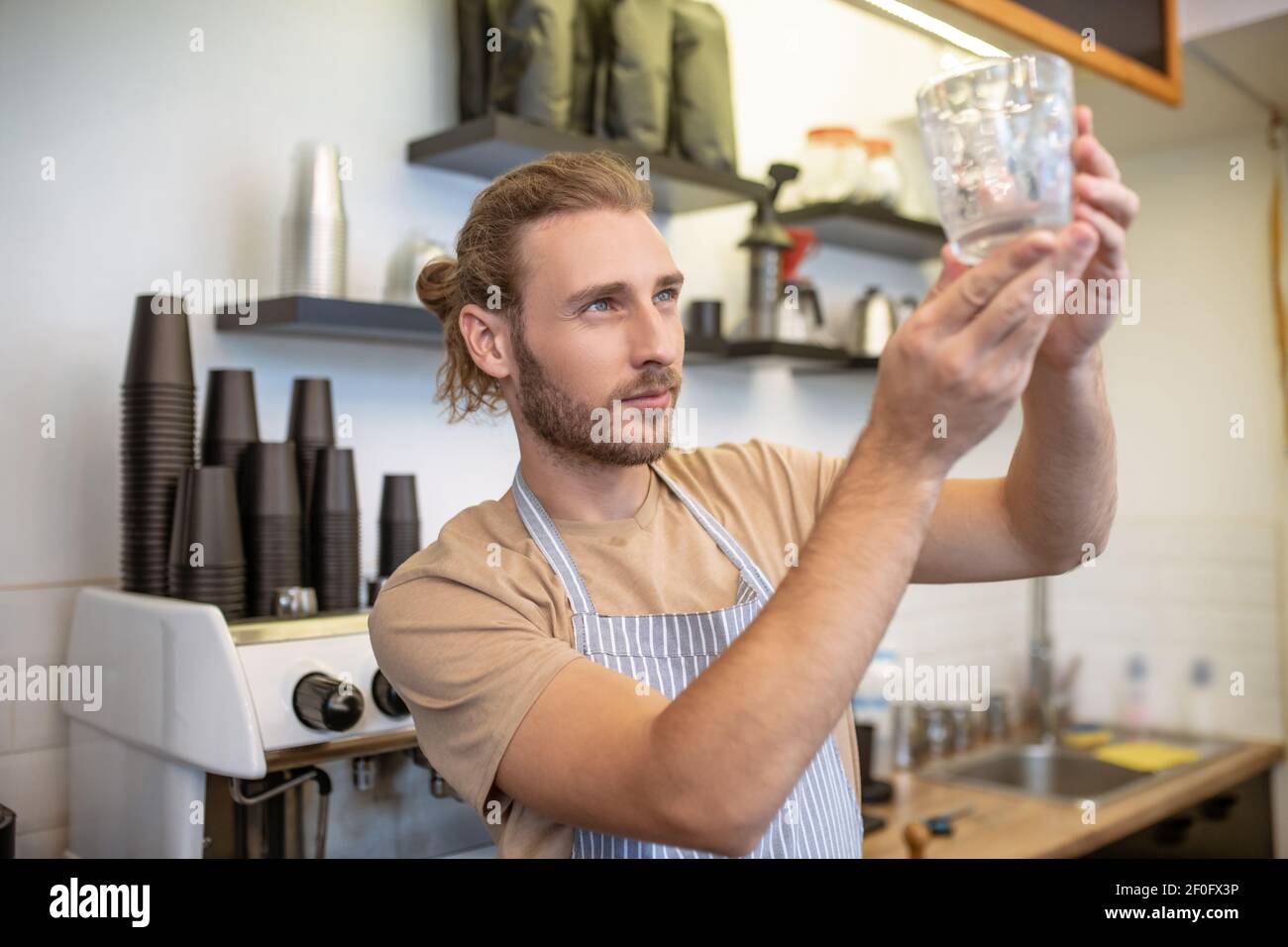 Homme attentif regardant le verre dans les mains levées Banque D'Images