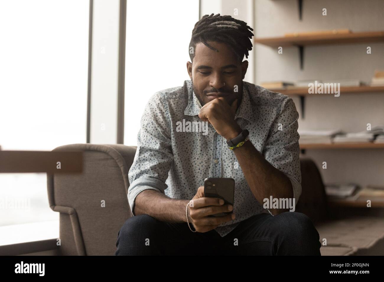 Gros plan un homme afro-américain satisfait regardant l'écran du téléphone Banque D'Images