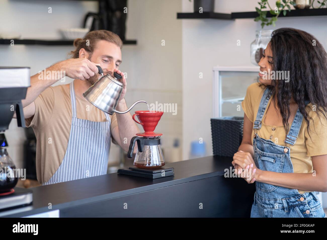 Un barista masculin prépare du café à l'aide d'un plongeur Banque D'Images