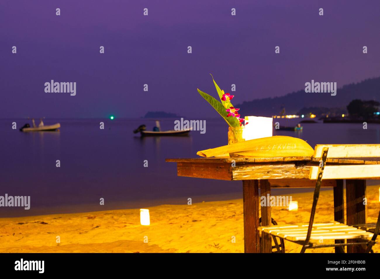 soirée au bord de la mer, tables dans le café décorées de fleurs, vacances sous les tropiques, arrière-plan flou Banque D'Images