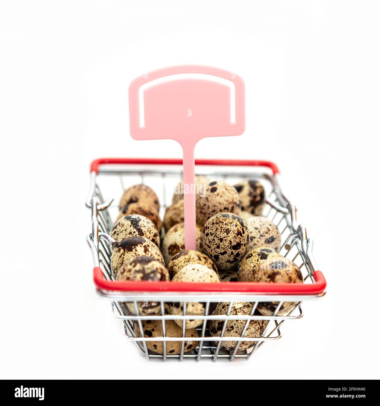 Œufs de caille crus dans le mini panier sur fond blanc. Pâques. Commerce en ligne. Shopping sur Internet Banque D'Images