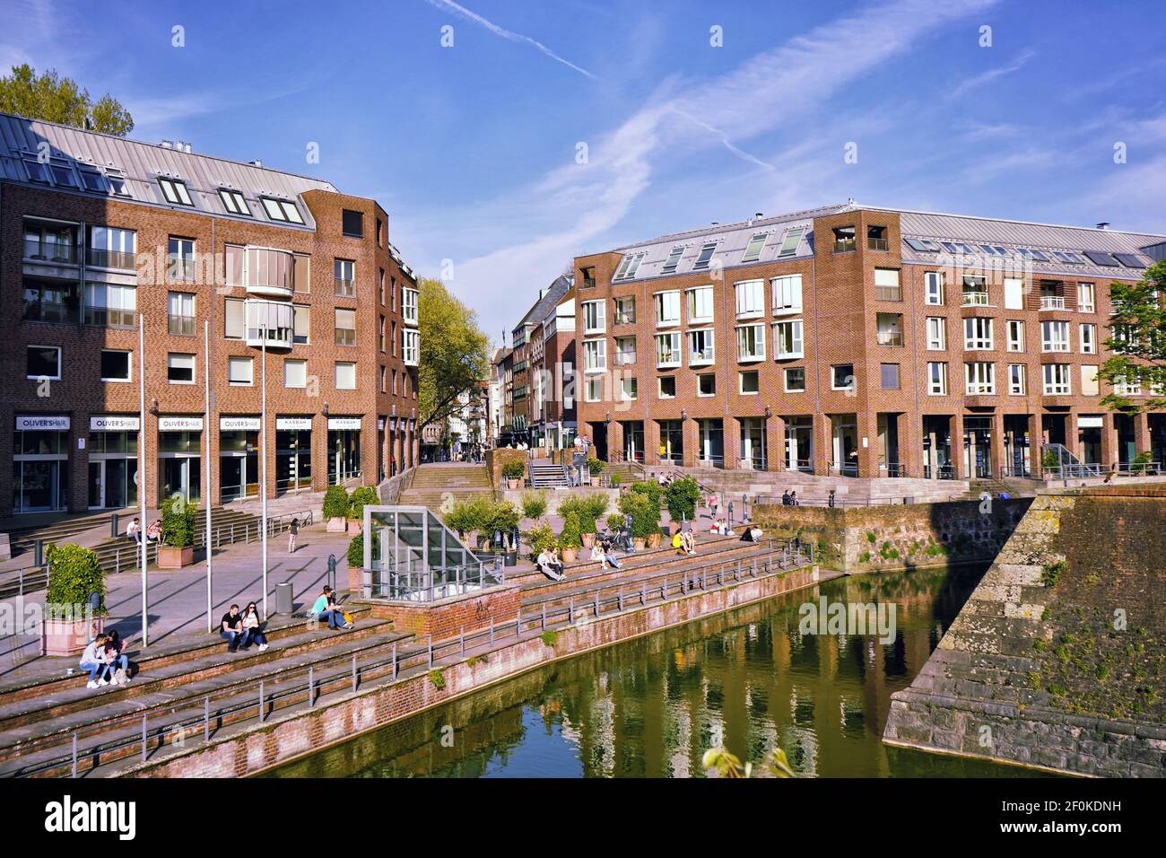 Les personnes qui s'assoyent sur les marches du « vieux port » près du Rhin et se détendent au soleil. Banque D'Images