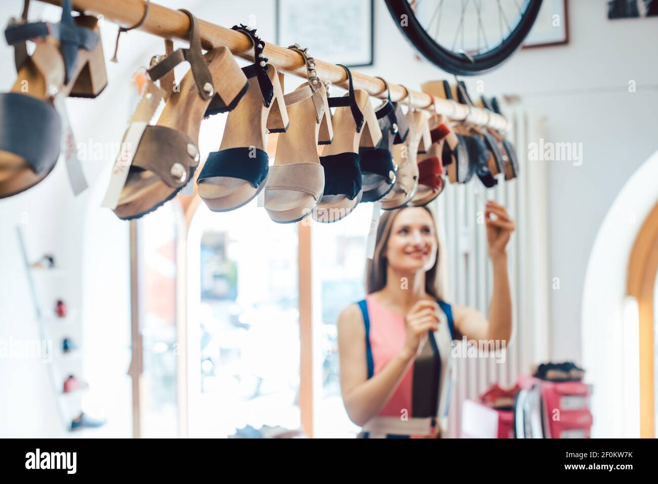 Femme regardant des chaussures pendantes du plafond dans le magasin Banque D'Images