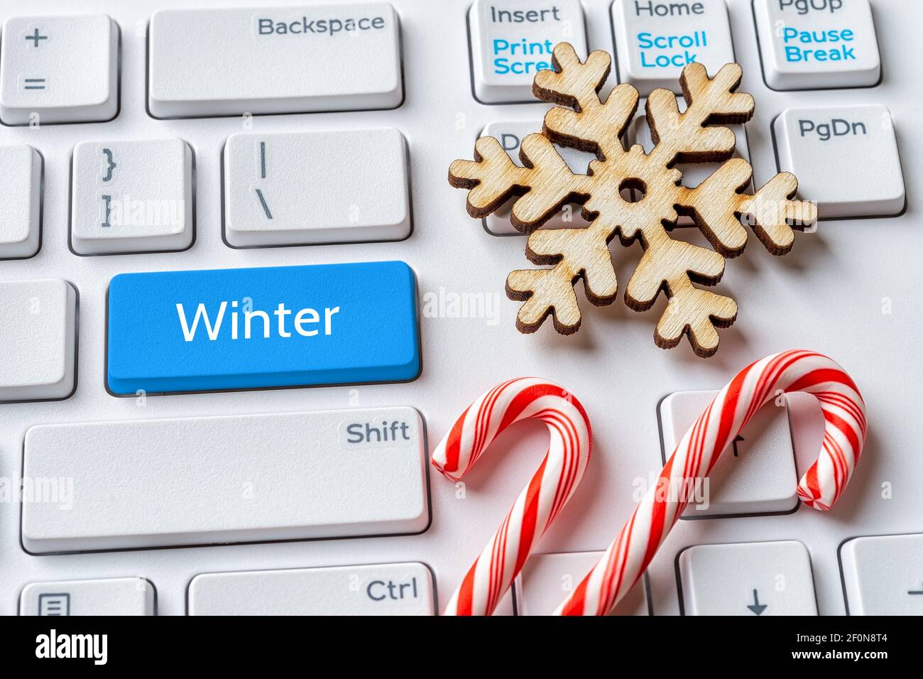 Touche bleue avec mot Winter, flocon de neige et Cannes de bonbons sur clavier PC blanc. Ventes d'hiver, vacances, Noël, concepts du nouvel an. Message sur la touche entrée. Banque D'Images