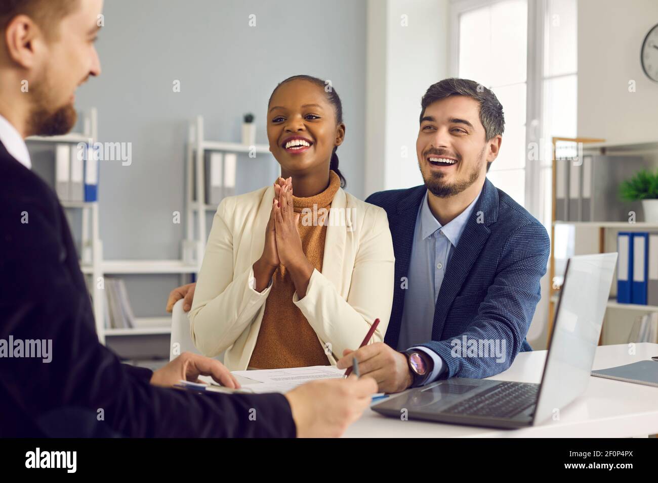 Joyeux jeune satisfait couple mixte d'origine ethnique merci gérant de banque courtier Banque D'Images