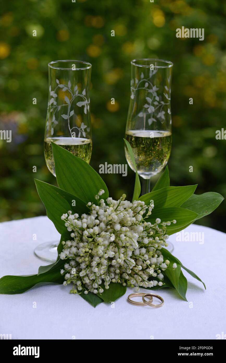 Symboles de mariage, bouquet de mariage avec anneaux de mariage et deux verres de vin mousseux sur UNE table blanche Banque D'Images
