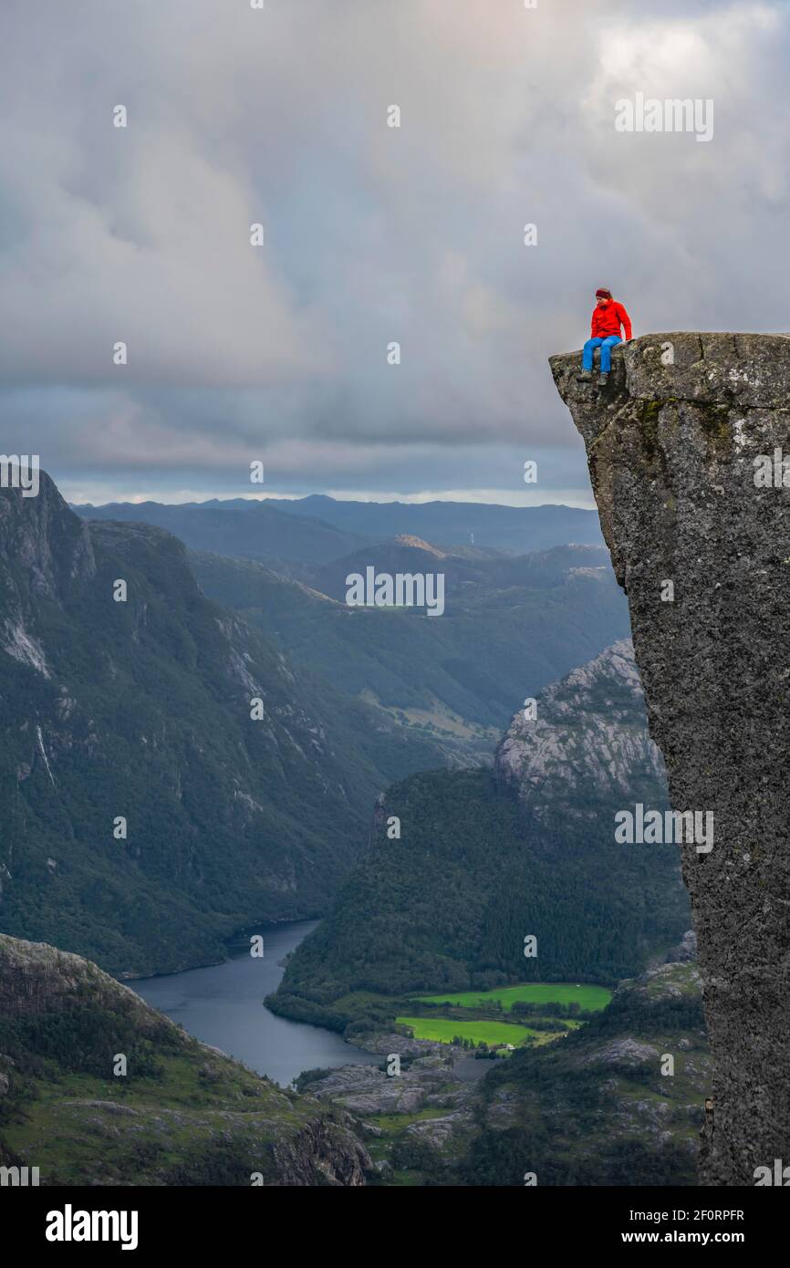 Personne seule assise au bord du plateau rocheux, chaire de roche de Preikestolen, Lysefjord, Ryfylke, Rogaland, Norvège Banque D'Images
