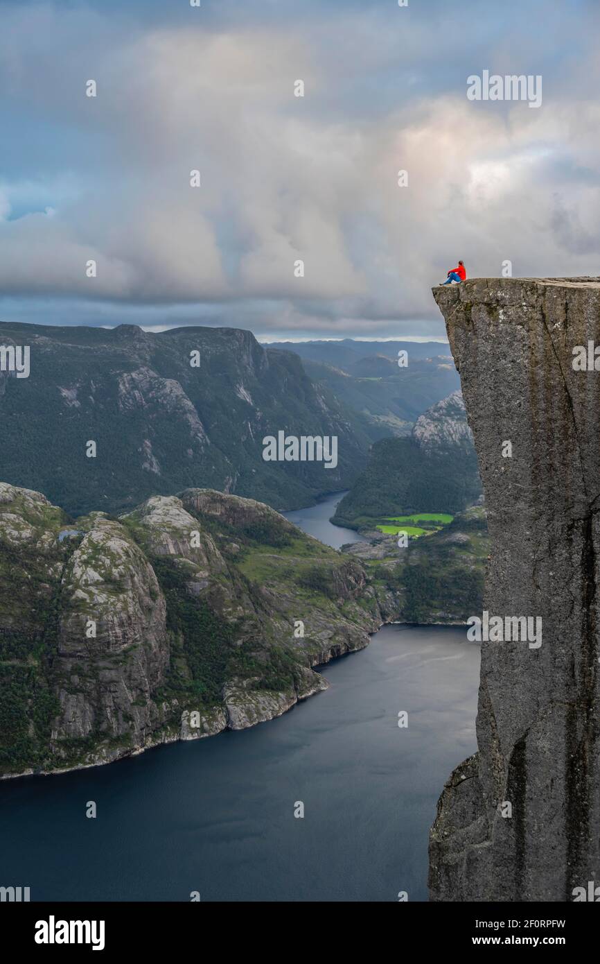 Personne seule assise sur le plateau rocheux, la flèche de Preikestolen, Lysefjord, Ryfylke, Rogaland, Norvège Banque D'Images