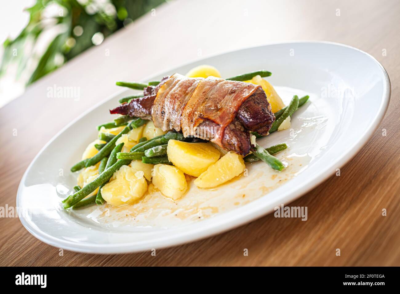 Plats cuits sur une assiette blanche - filet de porc avec soutien-gorge, pignons de pin et oignons de printemps. Banque D'Images
