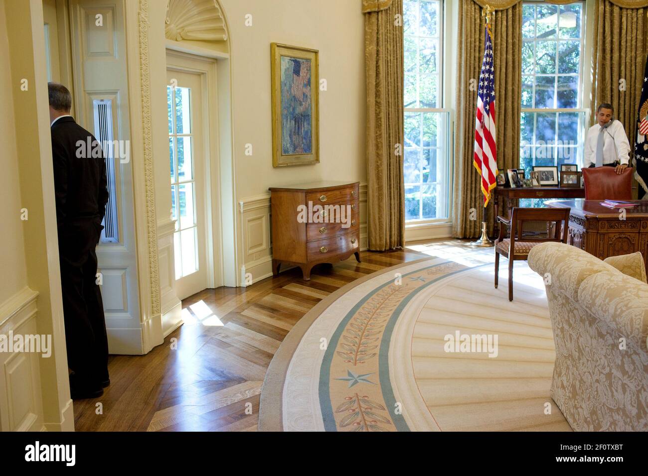 L'assistant du président pour les affaires législatives Phil Schiliro regarde la fenêtre pendant que le président Barack Obama parle au téléphone dans le bureau ovale octobre 8 2009. Banque D'Images