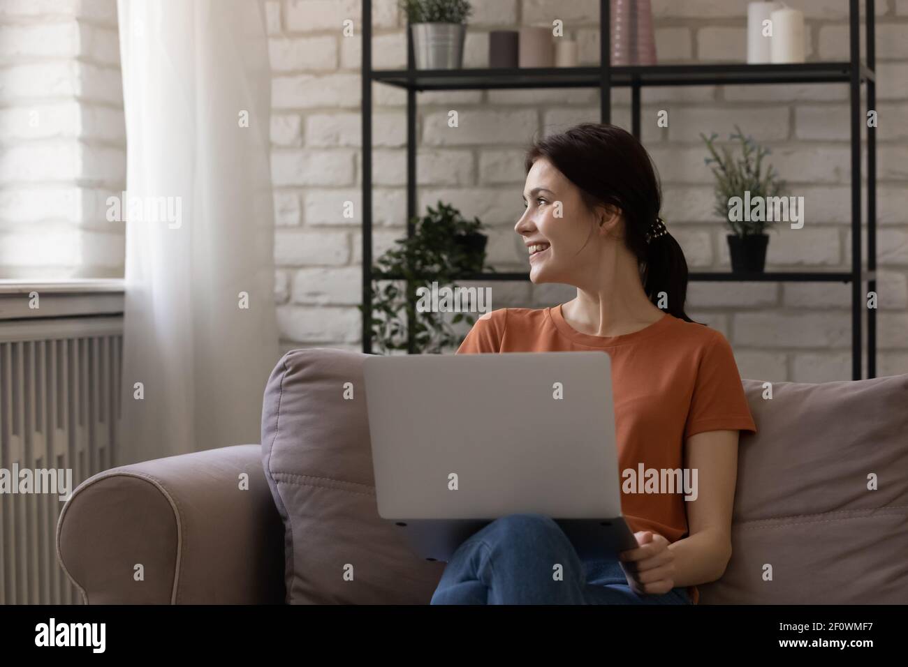 Une adolescente souriante et rêveuse distraite de l'écran d'un ordinateur portable. Faites une pause Banque D'Images