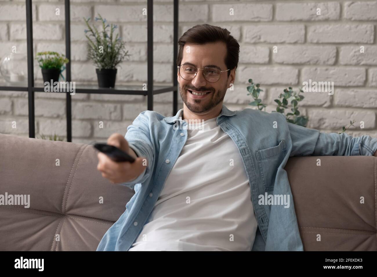 Millenny Guy regarder la télévision à la maison tenir la télécommande de tv Banque D'Images
