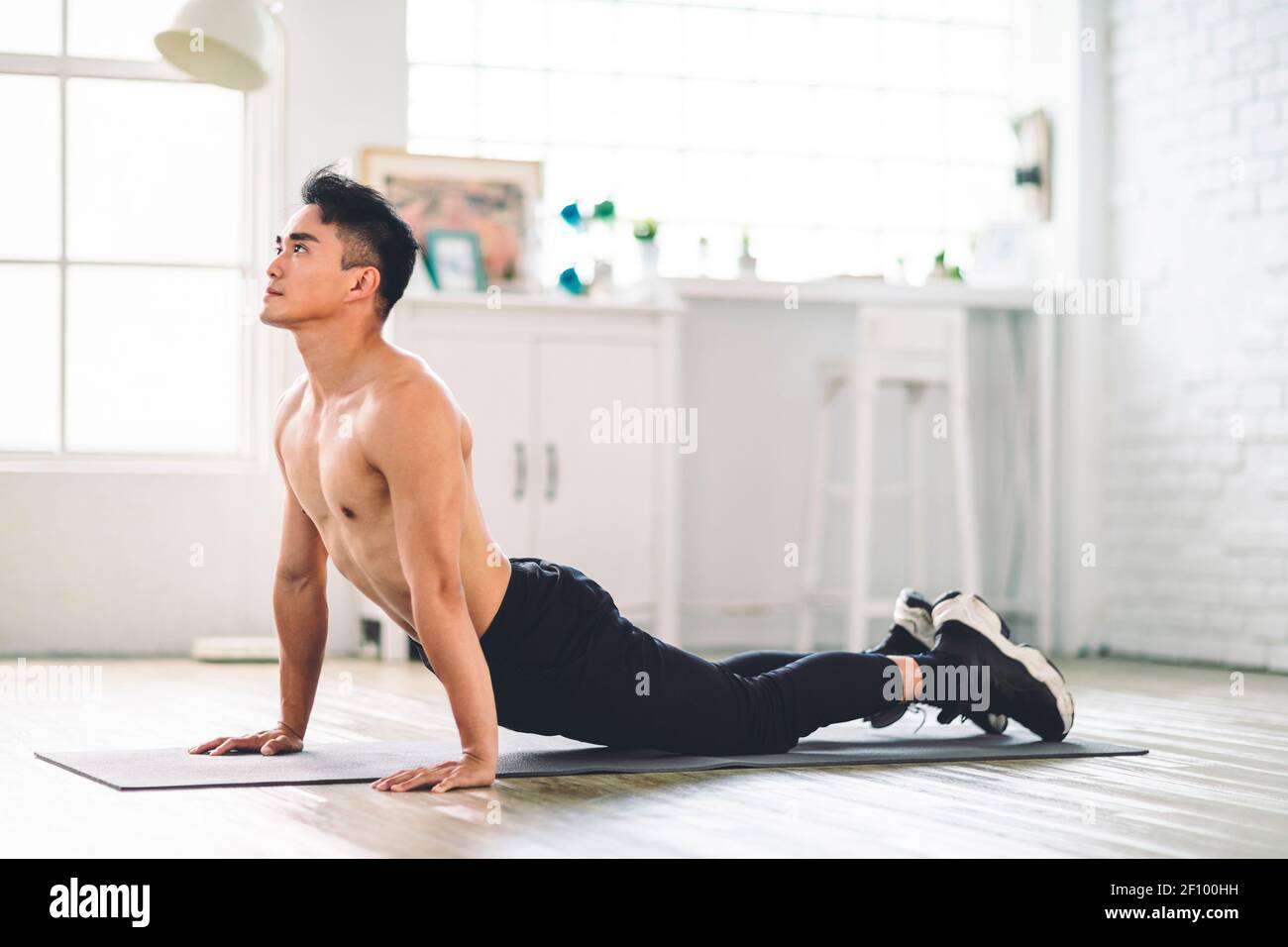Un jeune homme asiatique musclé fait des exercices sur le sol à la maison Banque D'Images