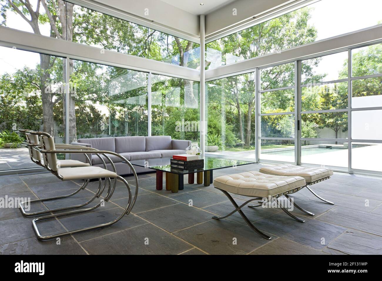 Le verre du sol au plafond fait entrer la lumière dans toute la maison  Schwartz, avec le mobilier minimaliste du salon (fauteuils et tabourets en  chrome et cuir Mies van der Rohe,