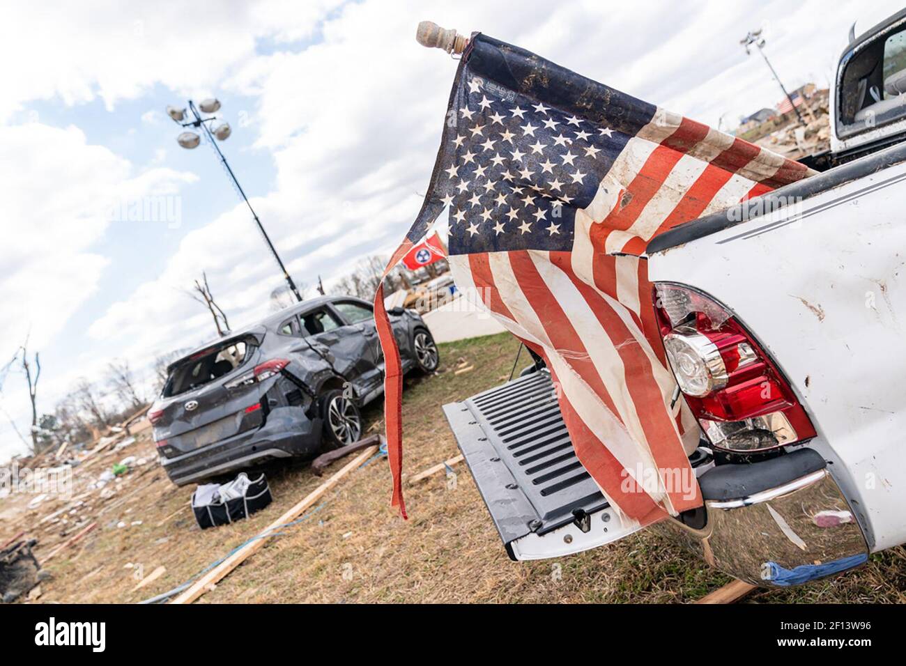 Un drapeau américain endommagé par la tornade est soutenu à l'arrière d'un camion dans le quartier ravagé par la tornade de Cookeville Tennessee. Vendredi 6 2020 mars où une tornade a frappé tôt le mardi 3 mars tuant 18 des 24 personnes tuées dans le centre du Tennessee. Banque D'Images