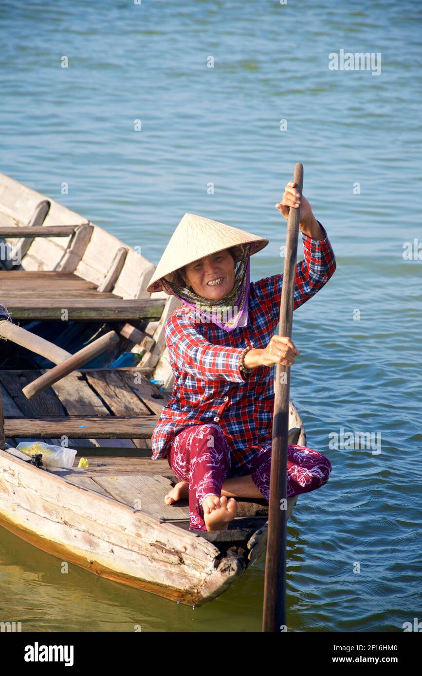 Femme vietnamienne en chapeau conique distinctif dans un petit bateau sur la rivière Thu bon, Hoi an, Vietnam. Banque D'Images