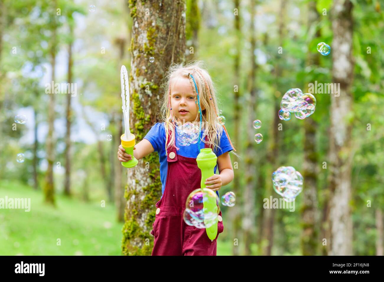 Bonne fille jouant avec des bulles de savon. Enfants actifs qui marchent dans le parc. Style de vie en famille, activités de plein-temps, vacances d'été avec les enfants. Banque D'Images