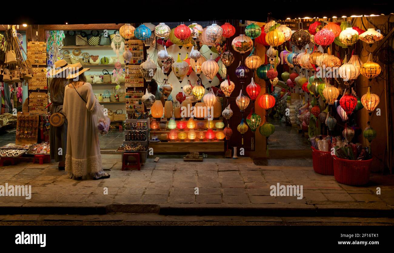 Touristes admirant les lanternes illuminées devant une boutique de souvenirs vietnamiens, Hoi an, Vietnam Banque D'Images