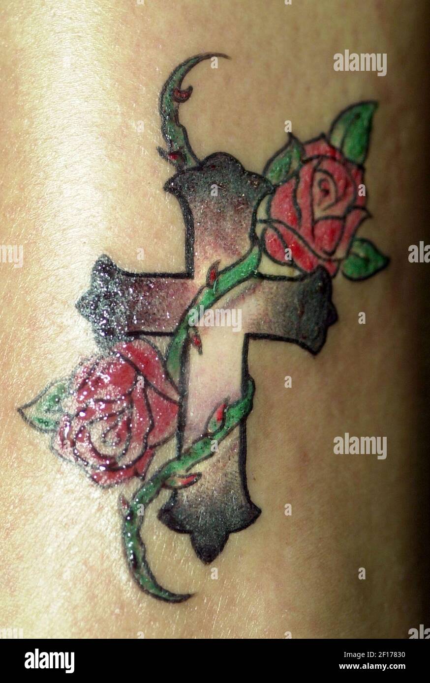 Un tatouage d'une croix sèche sur la jambe de Maria Arana, au salon