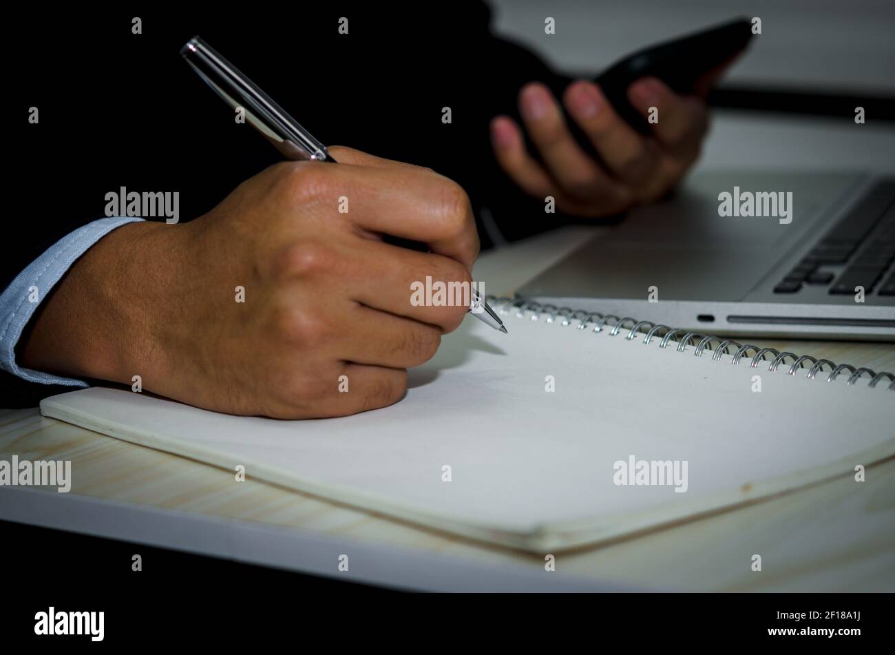 Homme main tenant un stylo pour prendre des notes sur le livre sur le bureau. Banque D'Images