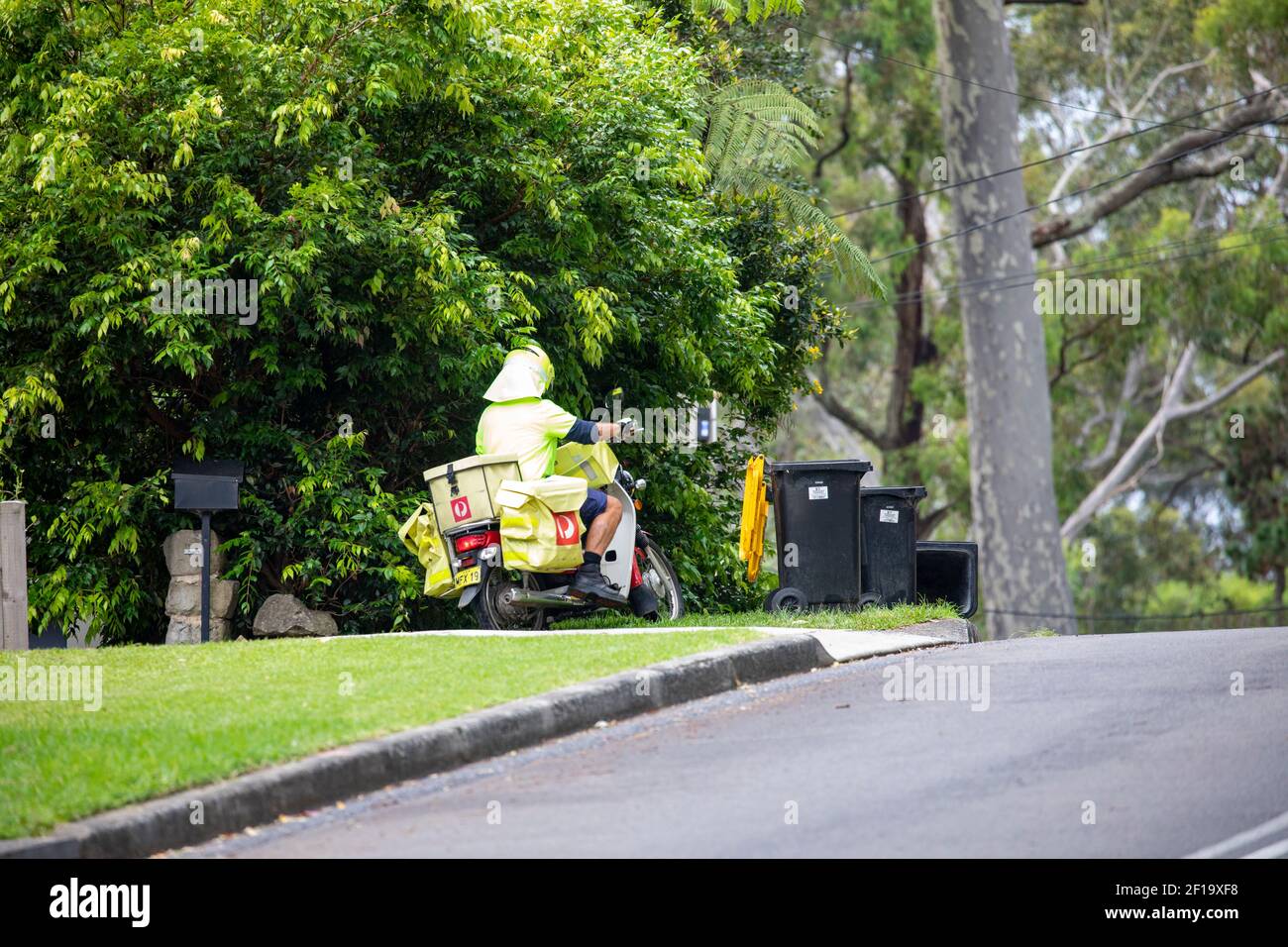 Un postier australien à moto livre du courrier et des lettres à un Maison à Sydney à Avalon, Nouvelle-Galles du Sud, Australie Banque D'Images