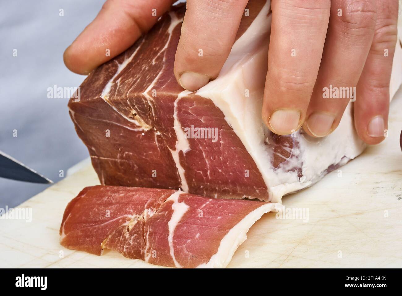 Jambon sec coupé en fines tranches gros plan sur les tranches de main du chef Prosciutto cuisine italienne Banque D'Images